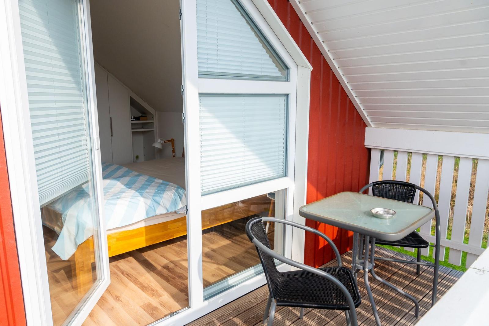 Terrasse mit Tisch und Stühlen neben Schlafzimmer mit Bett und Holzboden.