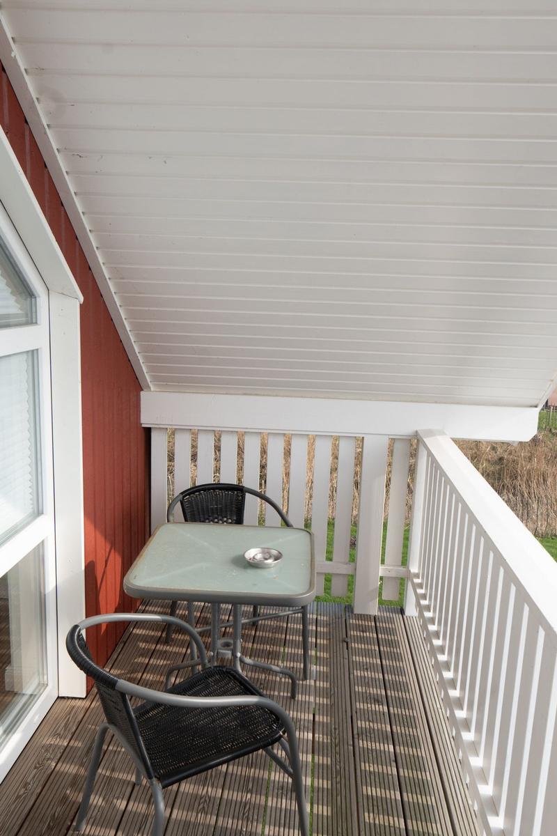 Terrasse mit Tisch und zwei Stühlen unter weißem Dach