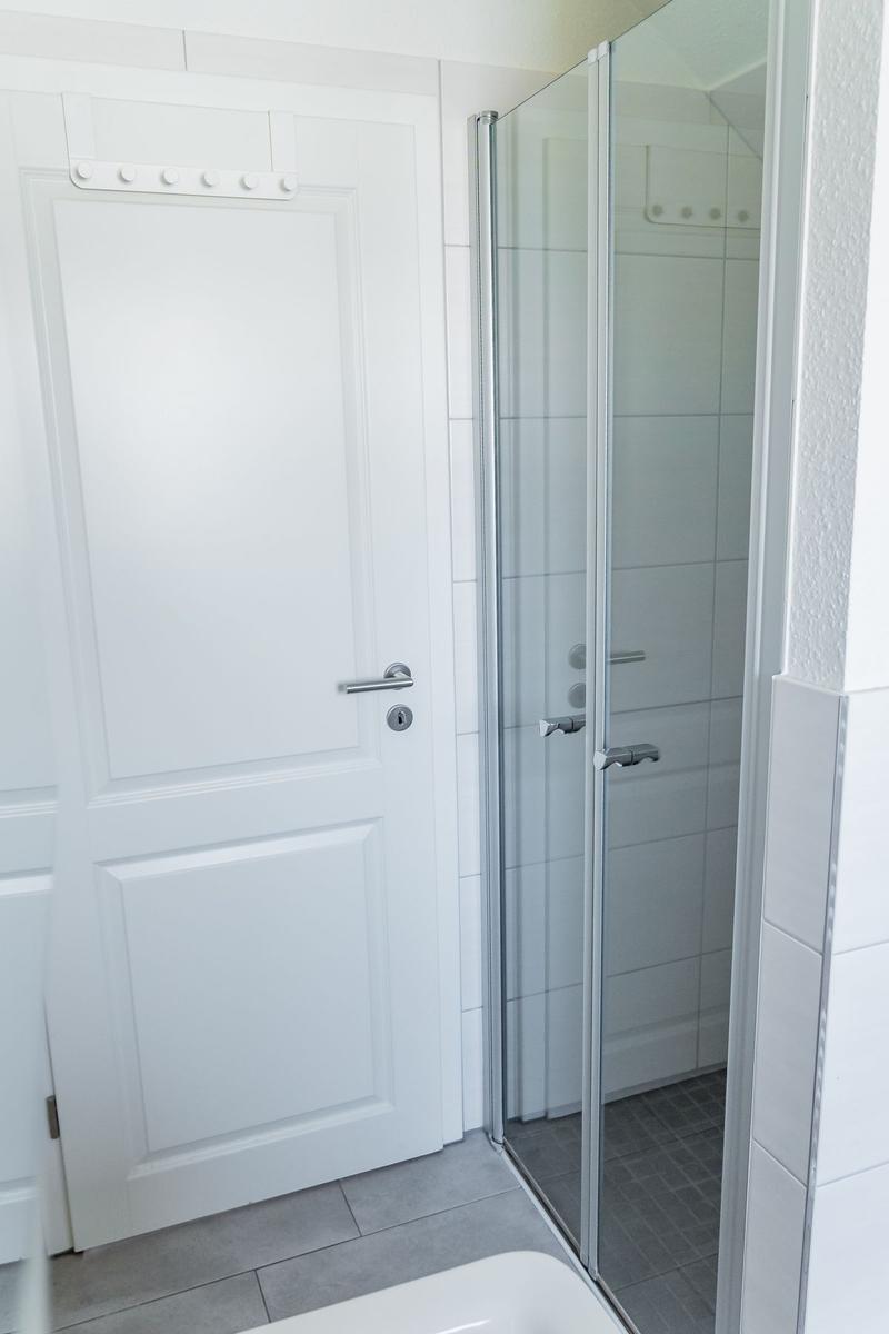 Badezimmer mit Dusche und weiße Tür.