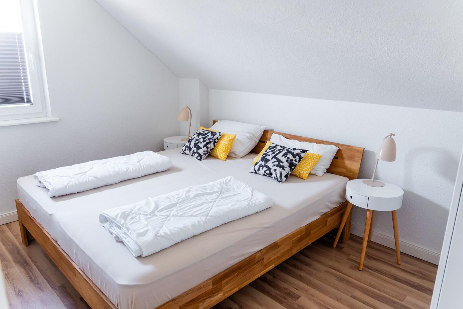 Schlafzimmer mit Doppelbett, zwei Nachttischen und Fenster.