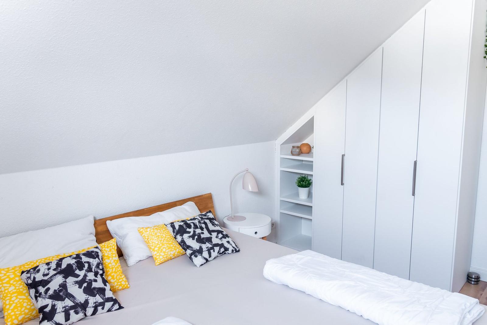 Schlafzimmer mit Bett, Kleiderschrank und Nachttisch.