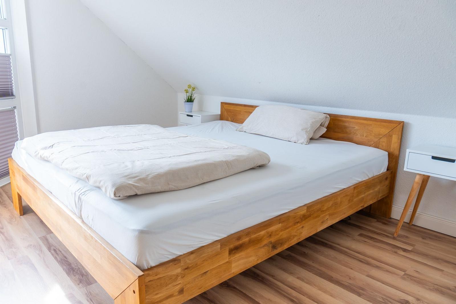Ein Schlafzimmer mit Holzbett, weißen Nachttischen und Holzboden.