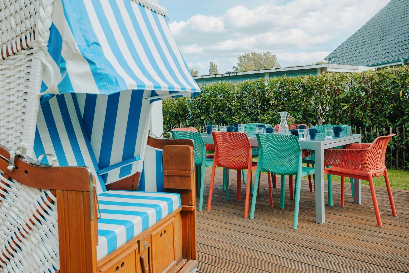 Terrasse mit Strandkorb und bunten Stühlen um Tisch