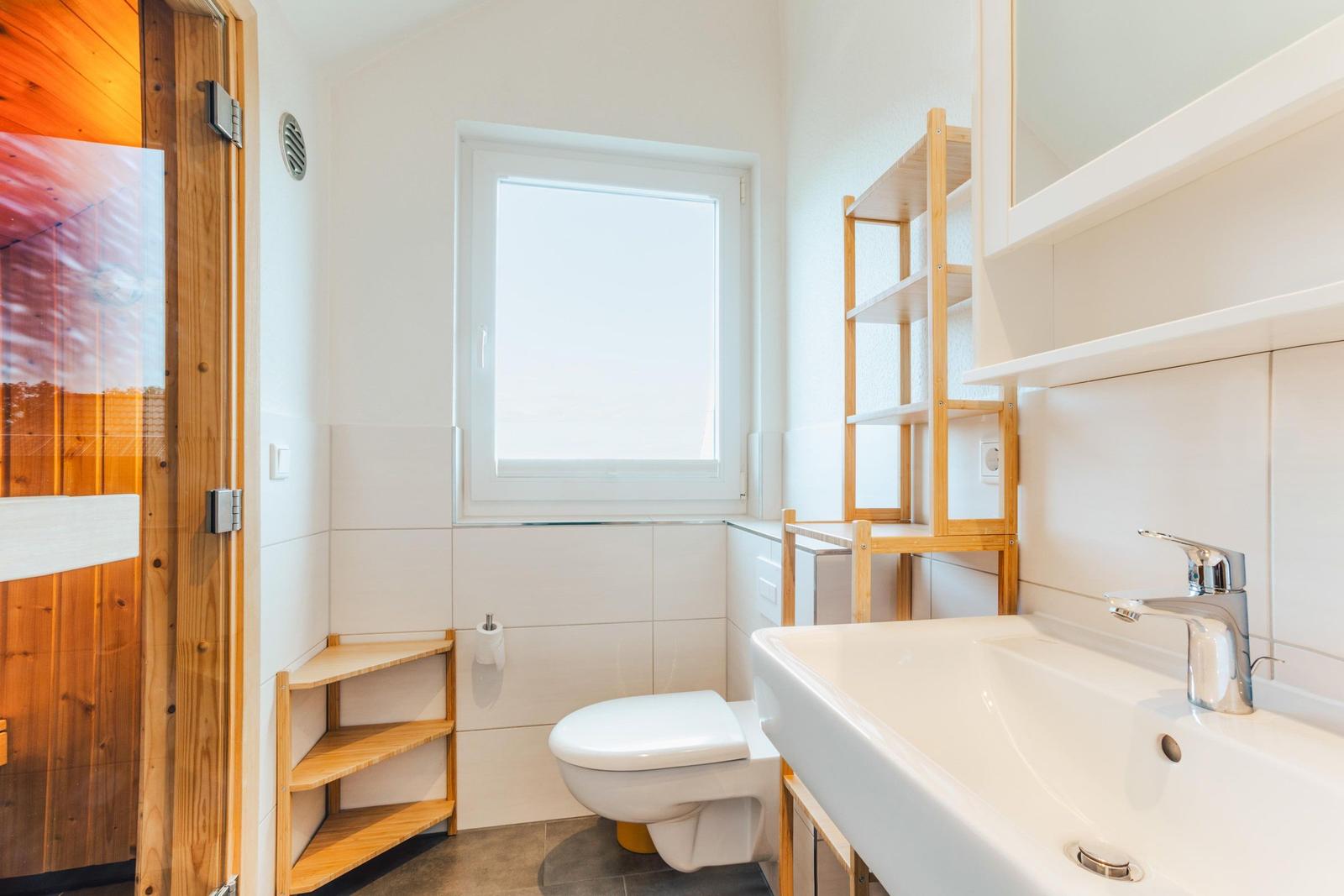 Badezimmer mit Waschbecken, Toilette und Fenster