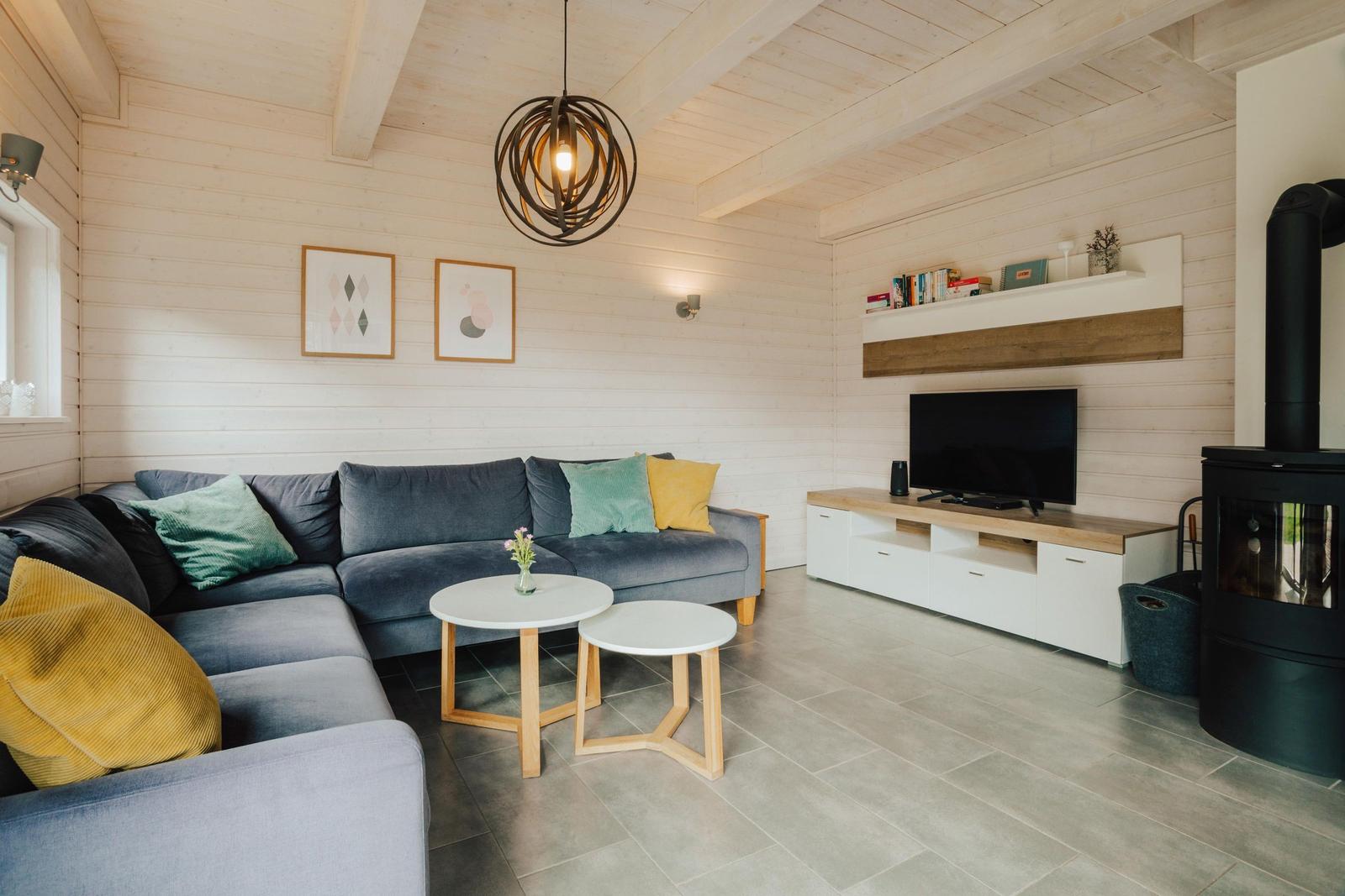 Wohnzimmer mit Sofa, TV und Kaminofen.