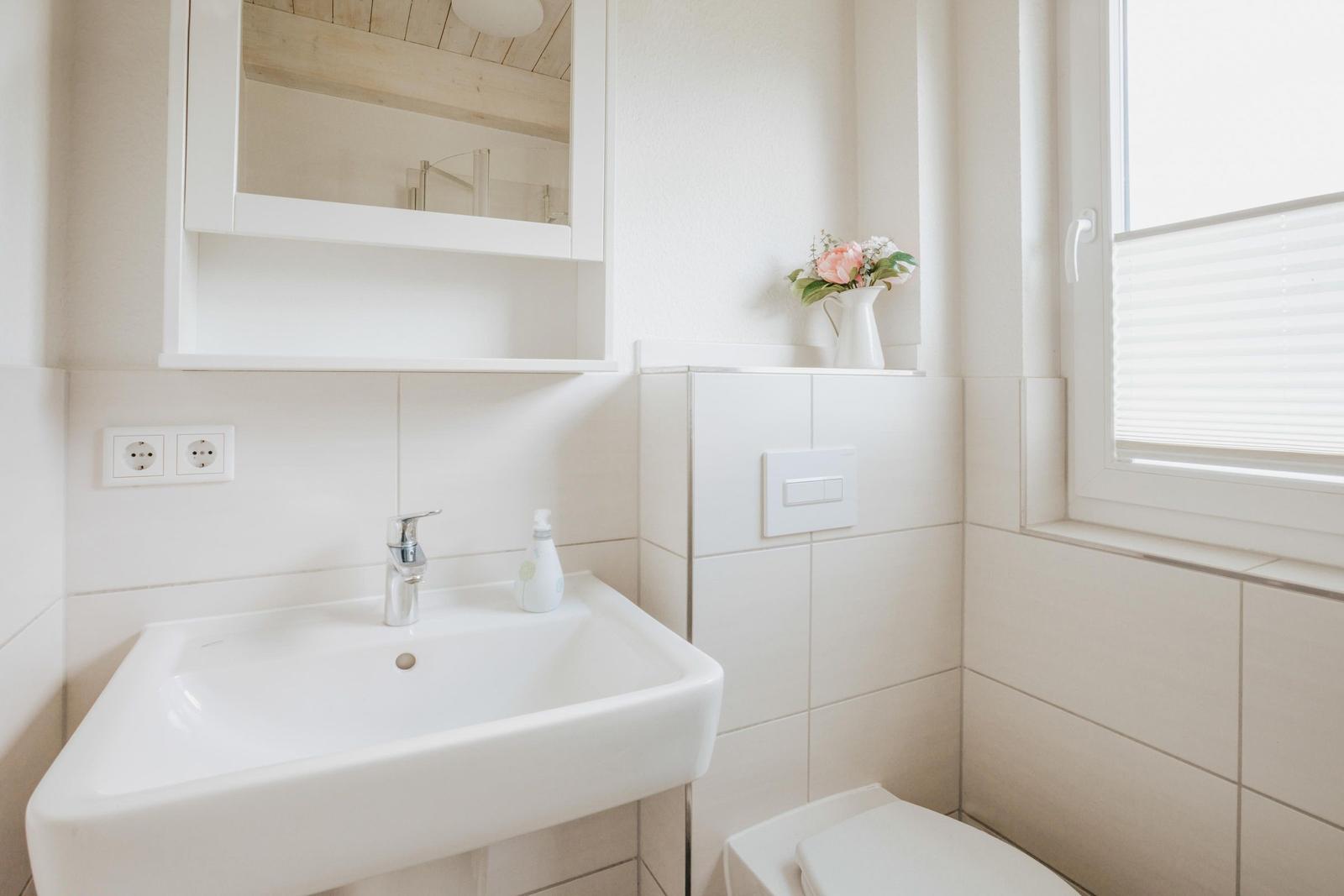 Badezimmer mit Waschbecken, Spiegel und Fenster