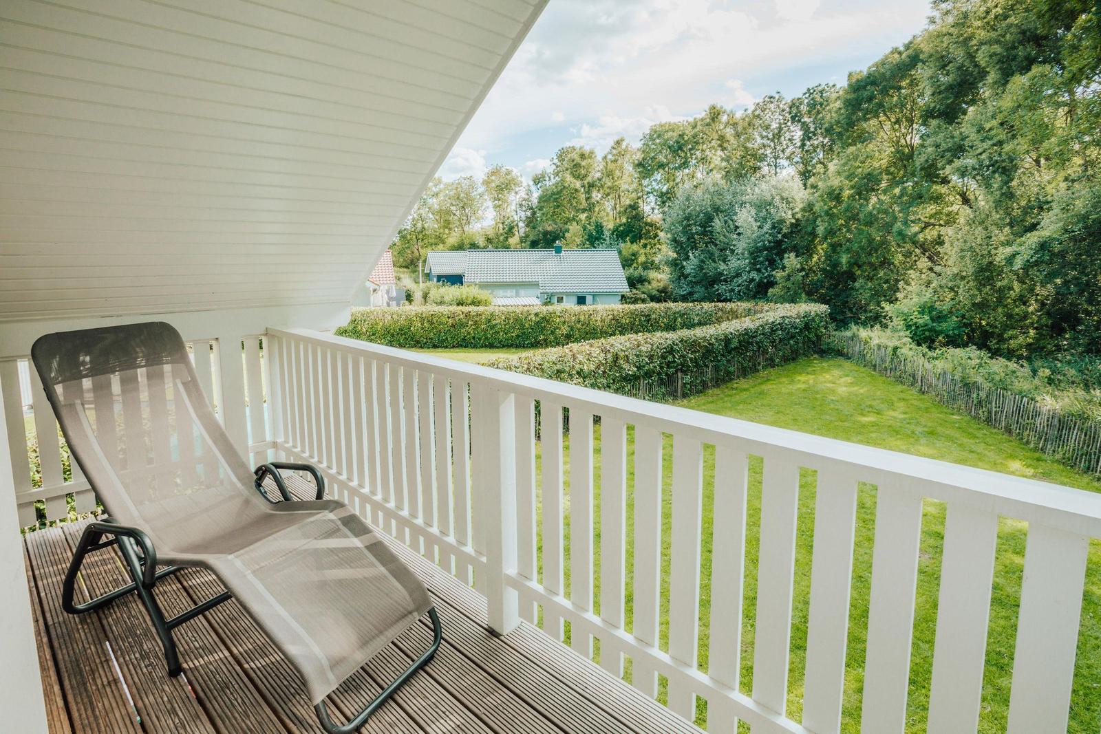 Terrasse mit Liegestuhl und Blick auf grünen Garten und Wald.
