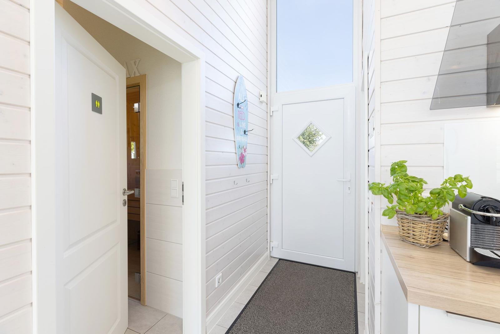 Helle Eingangshalle mit Küchenzeile und Tür zum Garten.