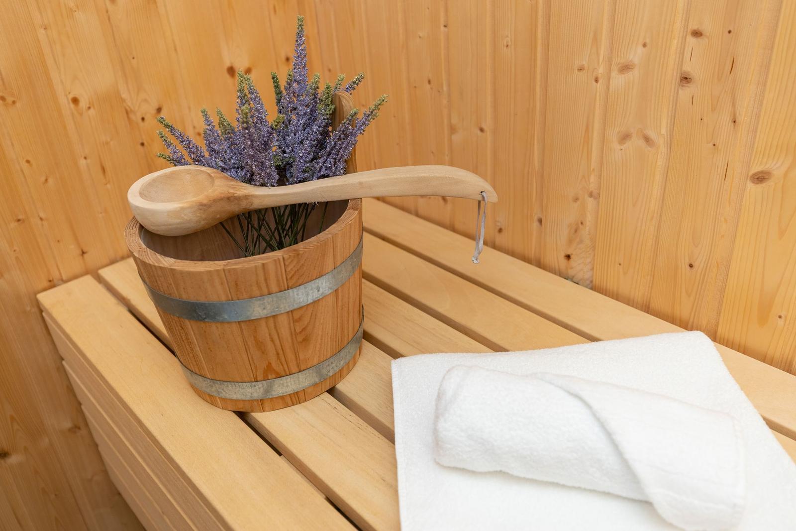 Holzwaschbecken mit Lavendel und Löffel auf Bank in Sauna