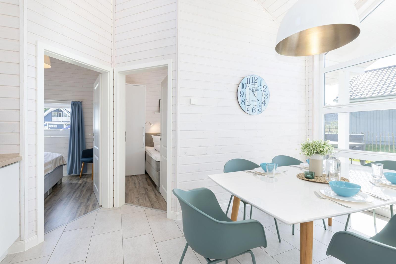 Essbereich mit Tisch, Stühlen und Wanduhr. Durchgänge zu Schlafzimmern.