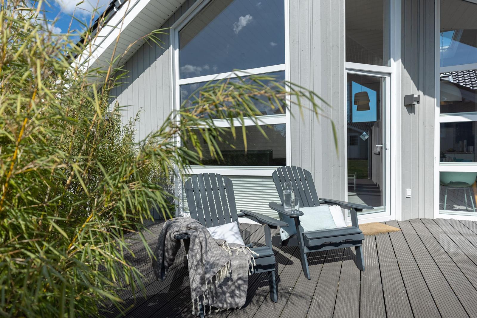 Terrasse mit zwei Stühlen, Glasfront und Bambuspflanze