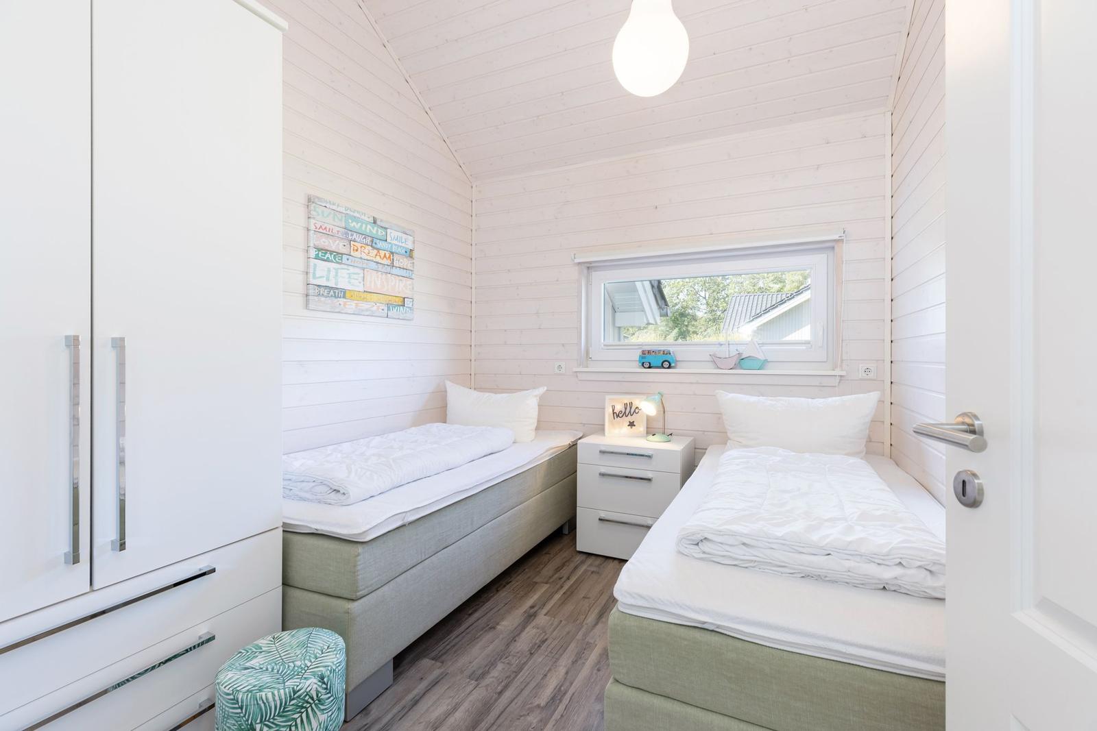 Zwei Betten, Schrank, Nachttisch und Fenster mit Blick.