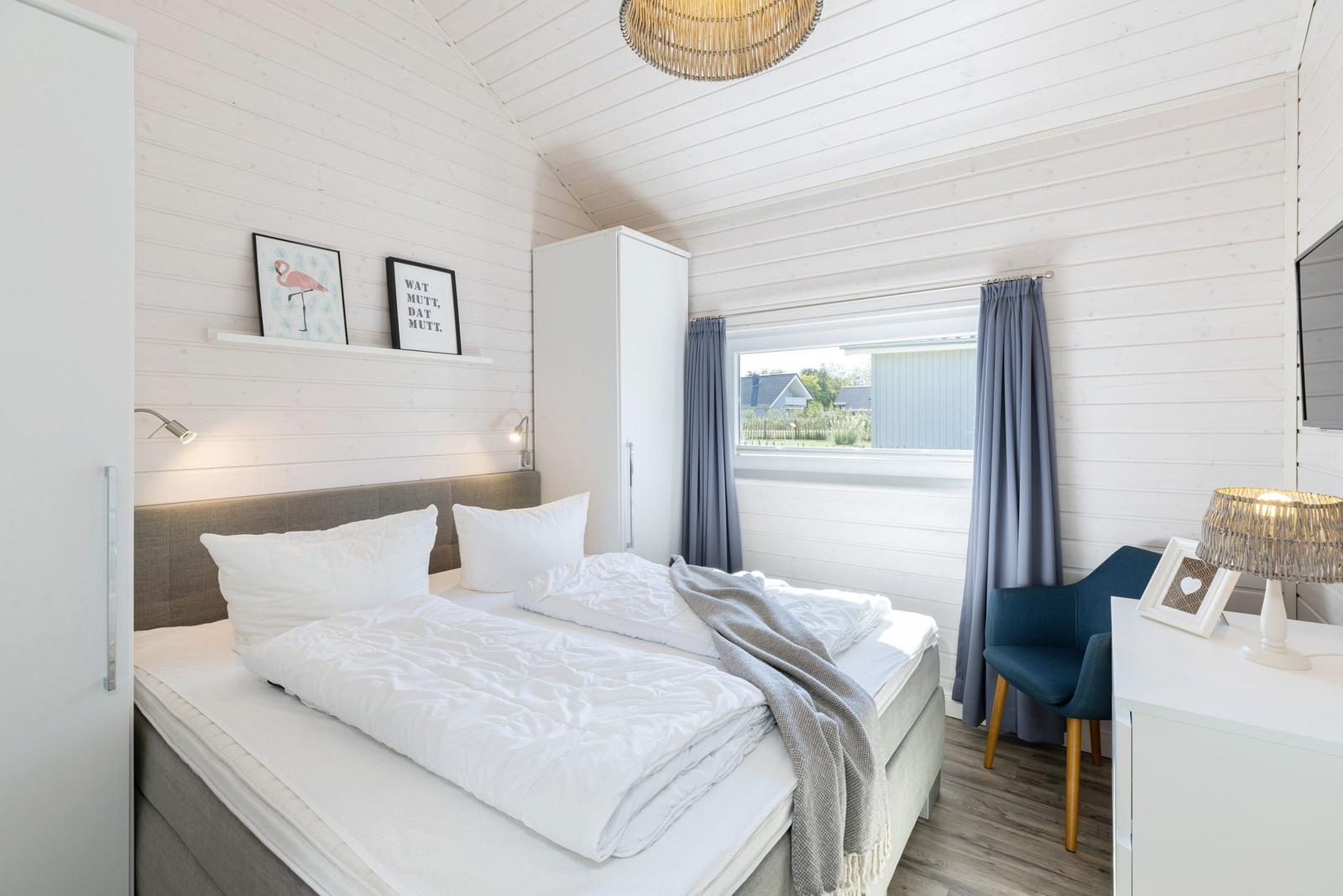 Schlafzimmer mit Doppelbett, Fenster und Schrank.