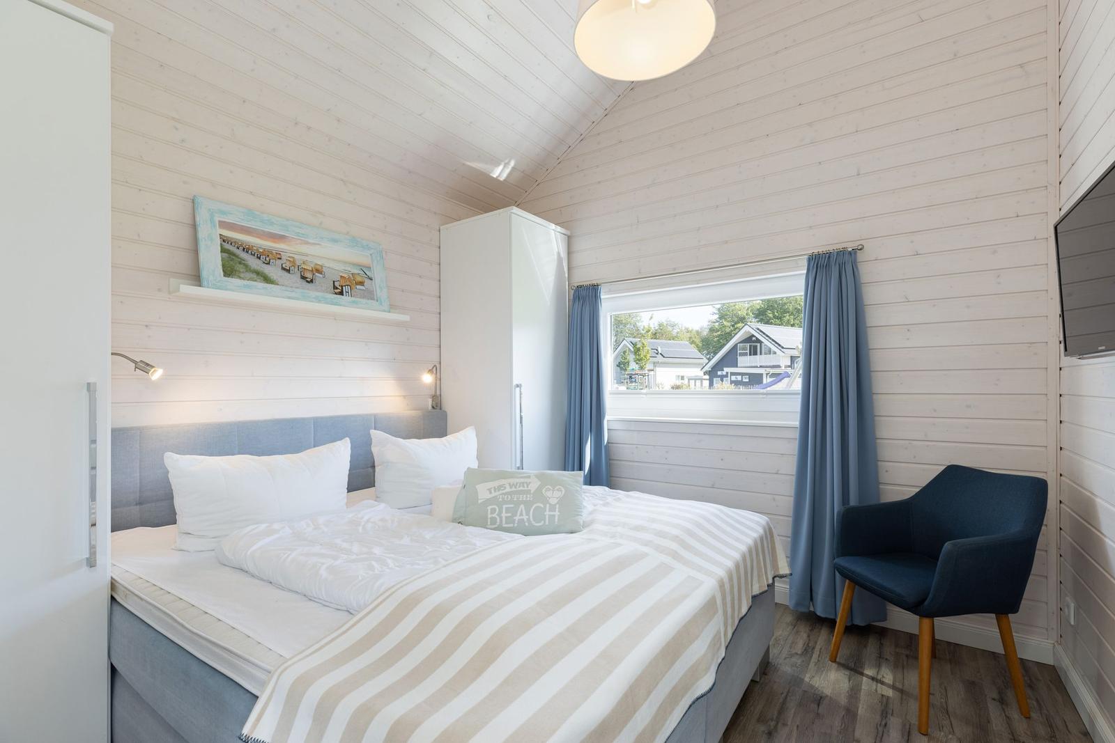 Schlafzimmer mit Bett, Stuhl und Fensterblick