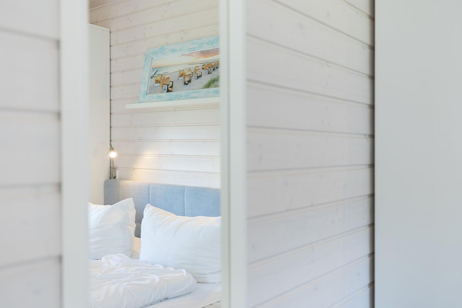 Schlafzimmer mit Bett, Wandbild und Nachttischlampe.