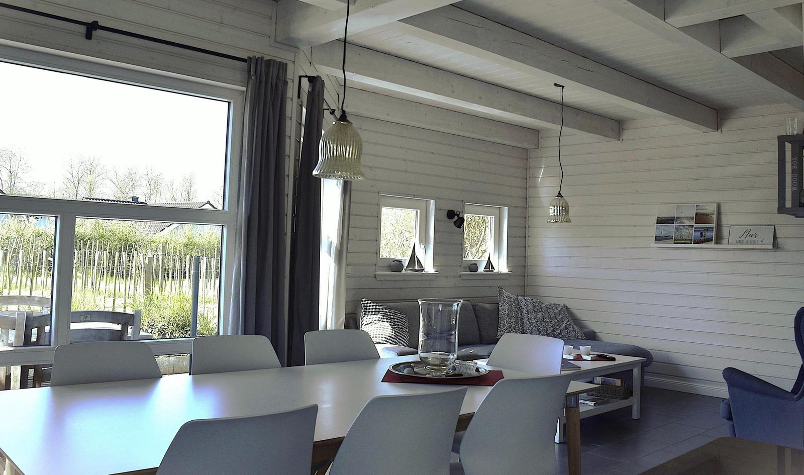 Essbereich mit Tisch und Stühlen, Sofa und Fenster zur Außenseite.