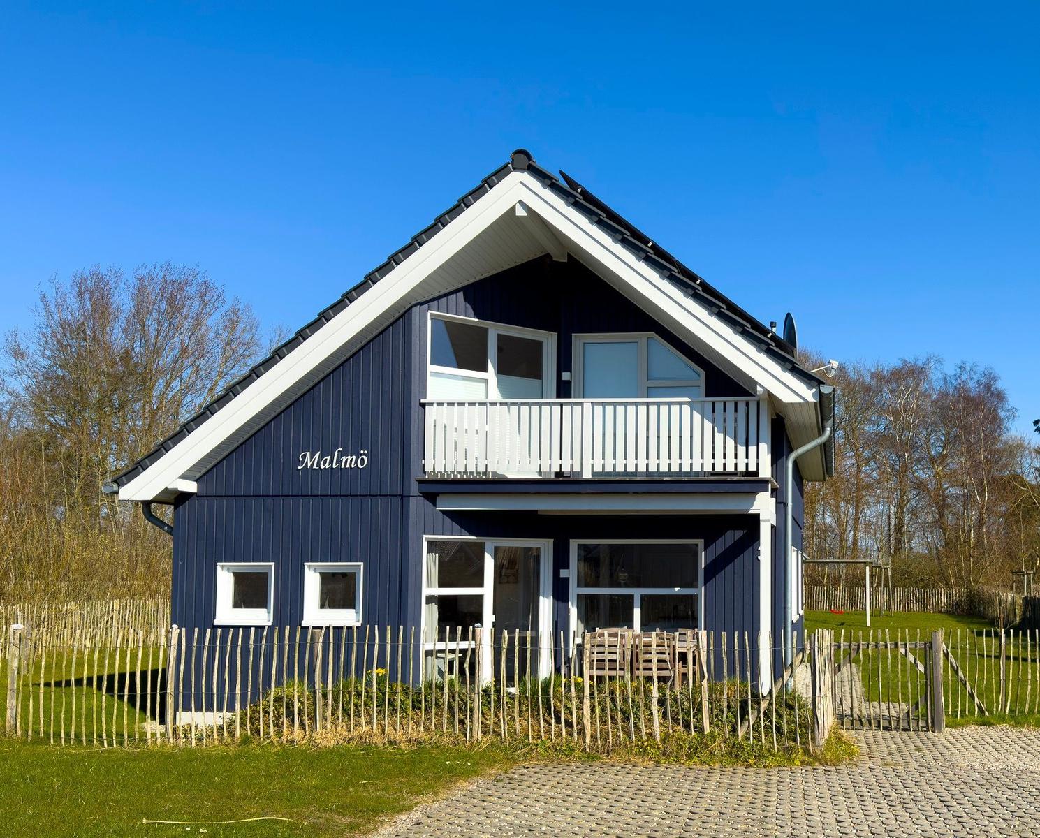 Blau gestrichenes Haus mit Balkon und Gartenzaun.