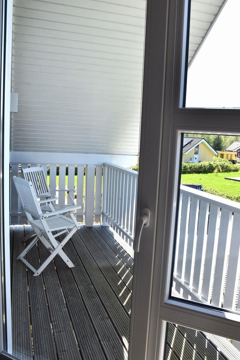 Terrasse mit zwei weißen Stühlen und Blick auf grünes Gras.