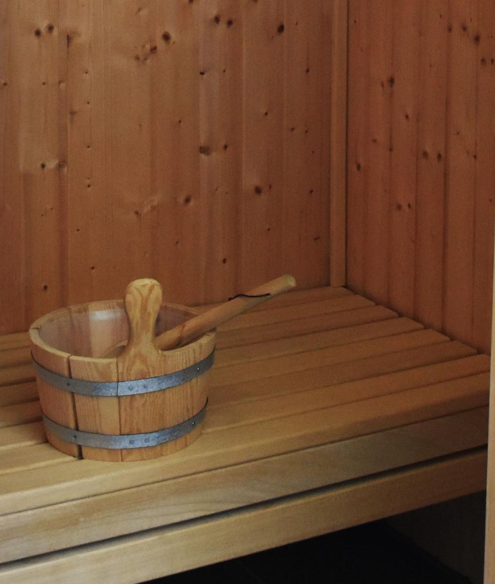Holzsauna mit Sitzbank und traditionellem Eimer mit Löffel.