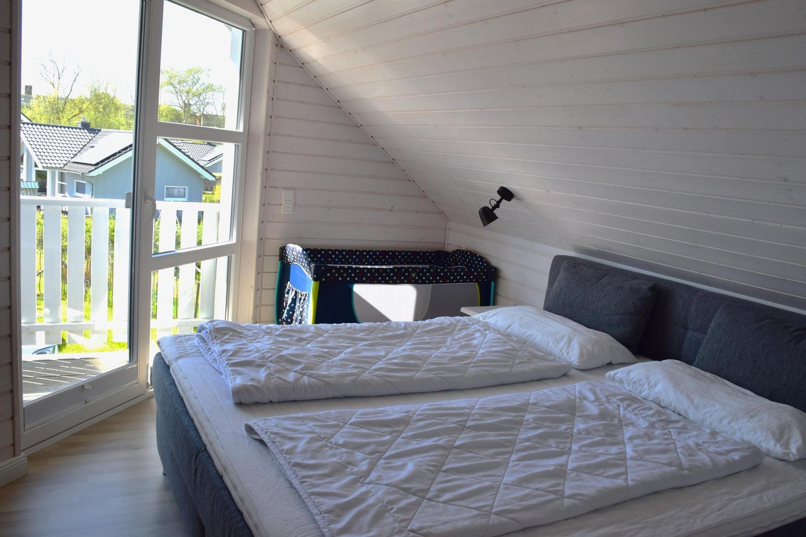 Schlafzimmer mit Doppelbett, Spielzeug und Balkonansicht.