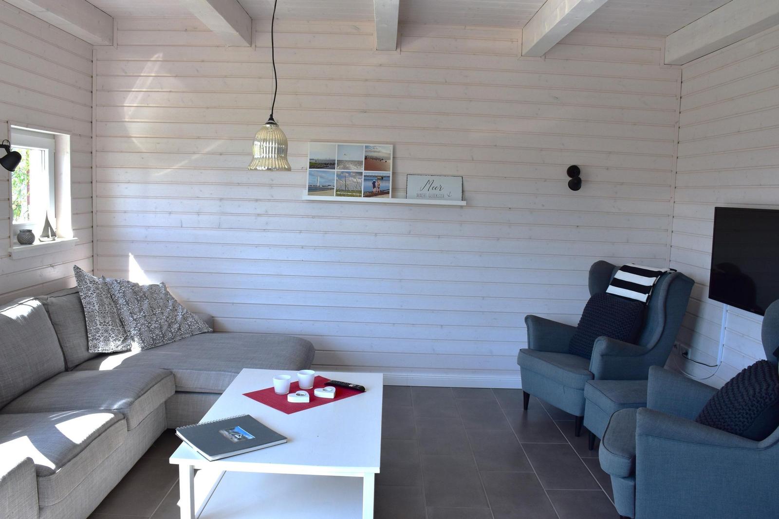 Wohnzimmer mit Sofa, Sesseln, Tisch und Wanddekoration.