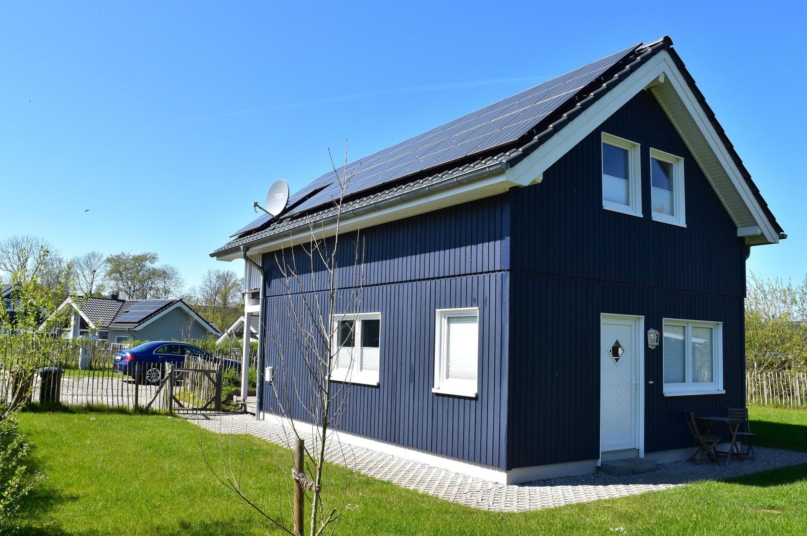 Ein zweistöckiges Haus mit Solaranlage auf dem Dach und weißer Tür.