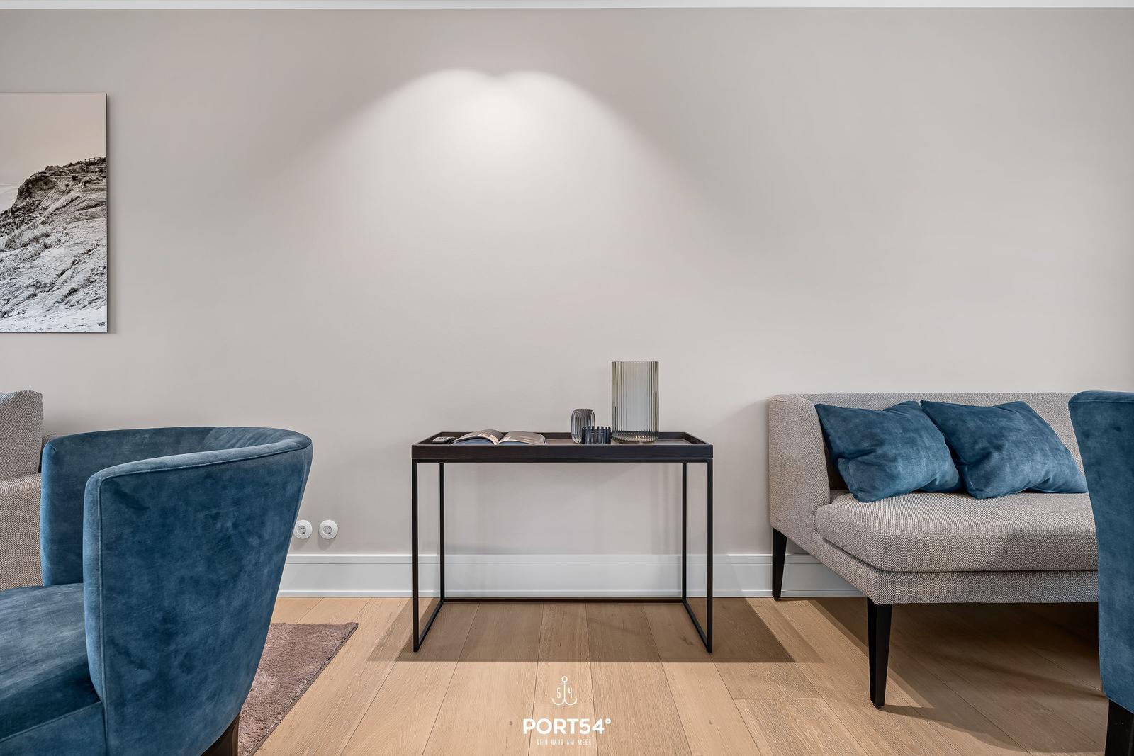 Ein Wohnbereich mit blauen Sesseln, einem grauen Sofa und einem Tisch.