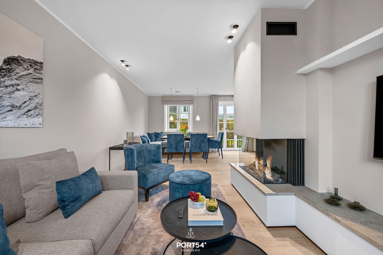 Wohn- und Essbereich mit Kamin und blauen Sitzgelegenheiten.