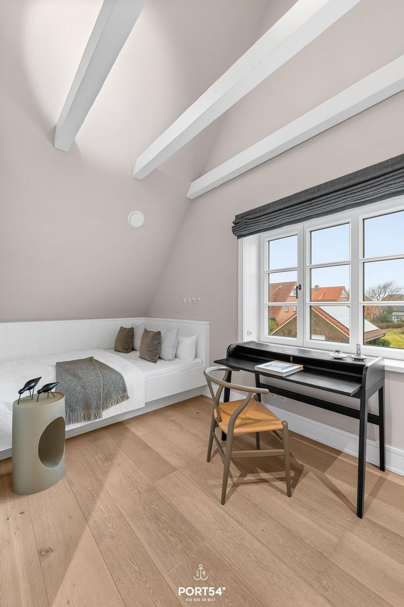 Schlafzimmer mit Dachschrägen, Bett, Schreibtisch und Fenster mit Blick.