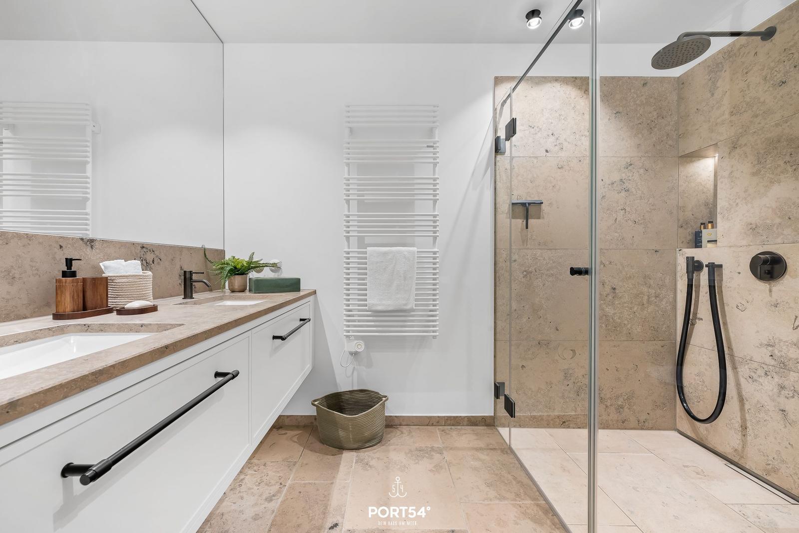 Badezimmer mit Dusche, Waschbecken und Heizkörper