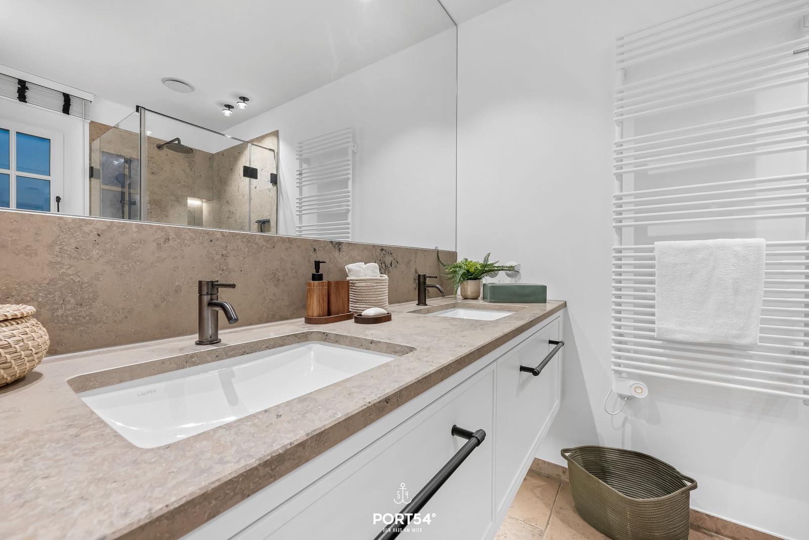 Badezimmer mit Doppelwaschbecken, Spiegelschrank und Heizkörper