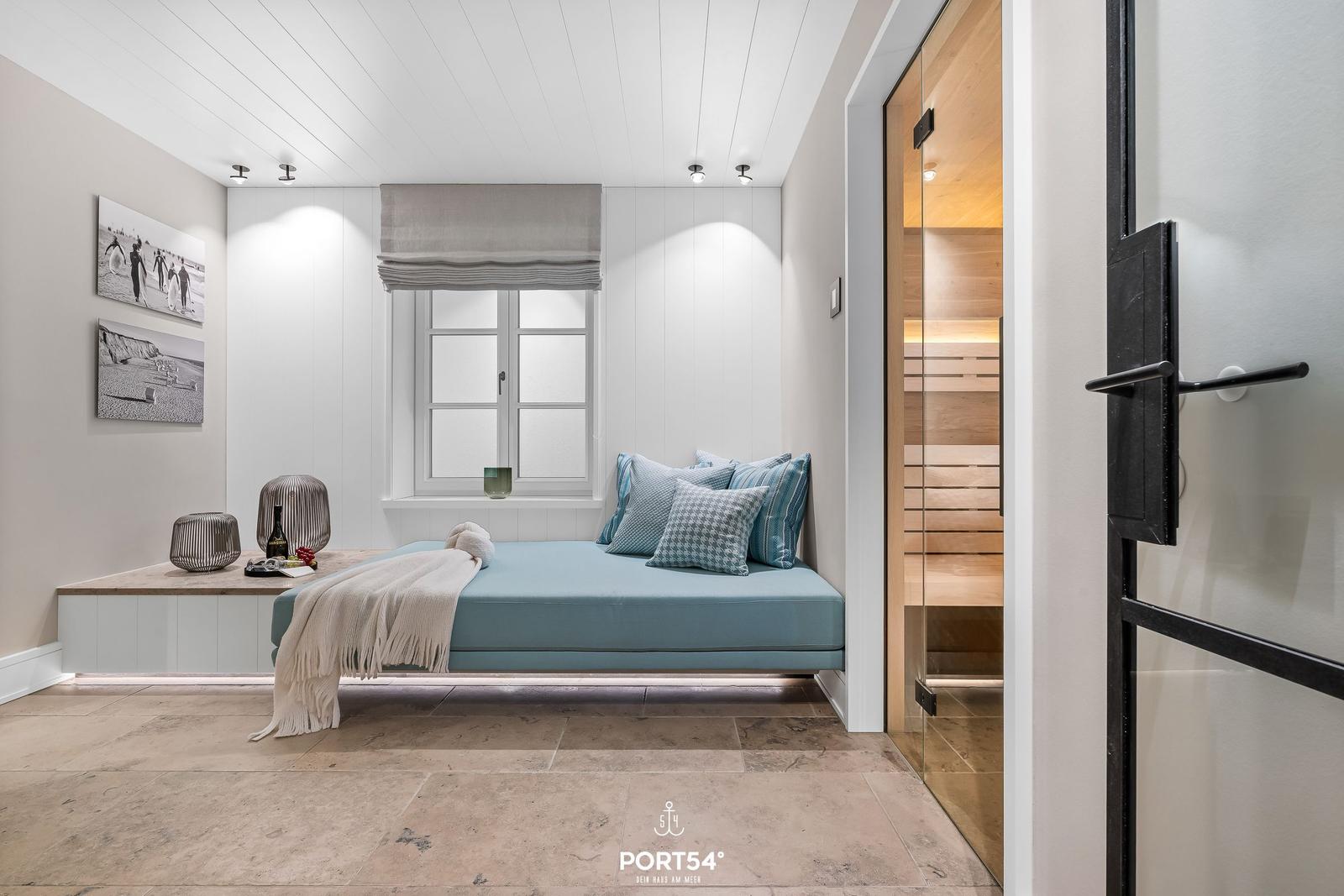 Ein Raum mit Bett, Fenster und Sauna. Wandbilder und Bodenfliesen sind sichtbar.