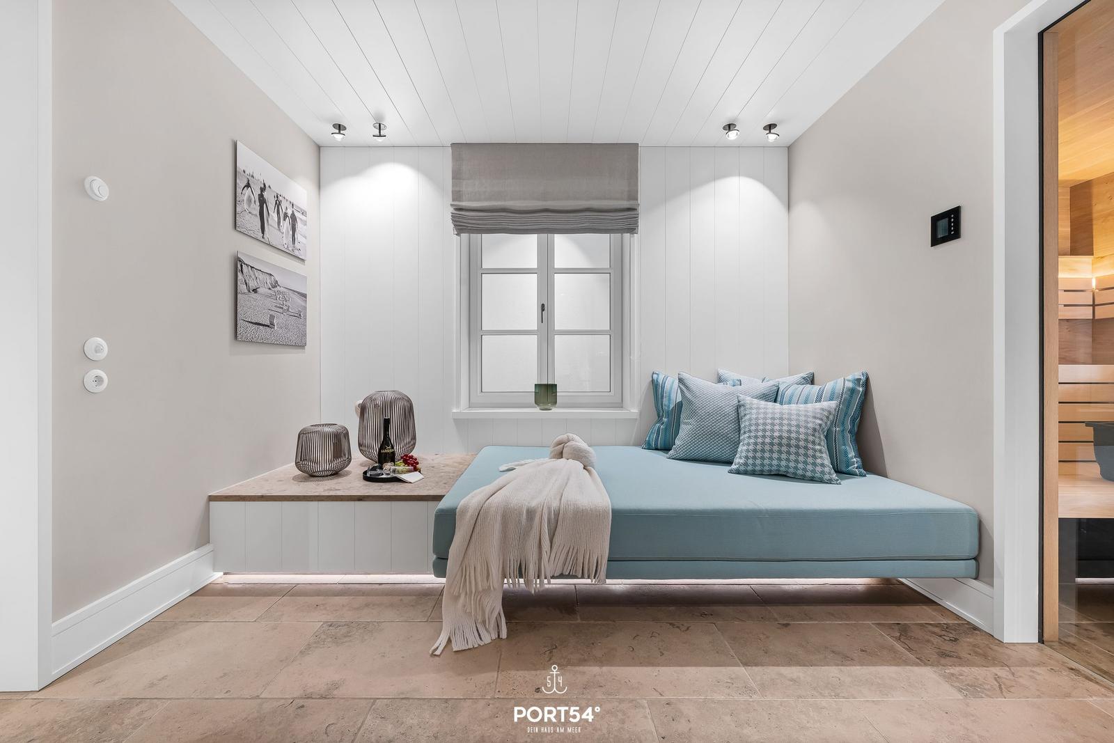 Schlafzimmer mit Bett, Fenster und Sauna im Hintergrund.