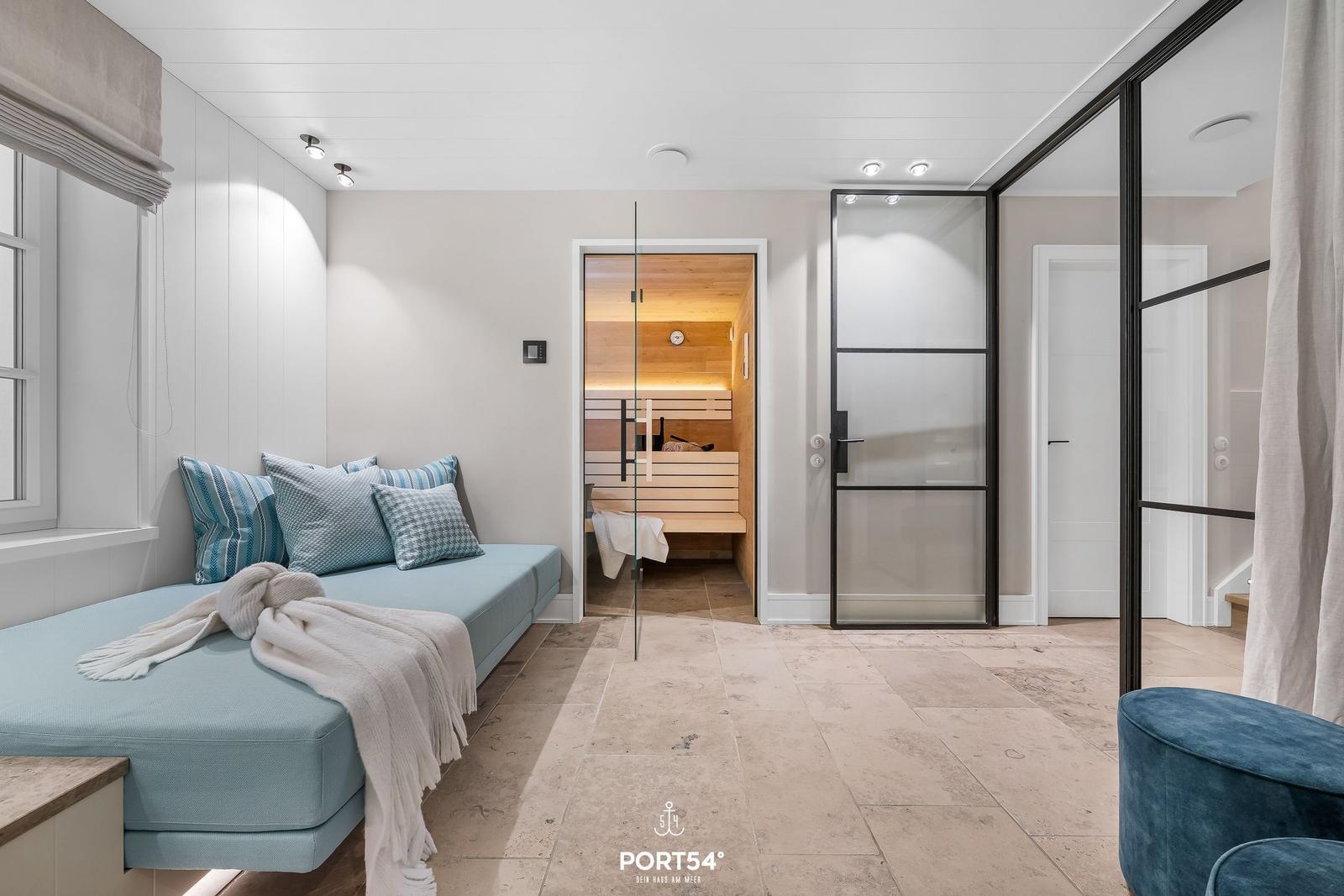Wohnbereich mit Sauna, Sitzbank und blauem Sessel.