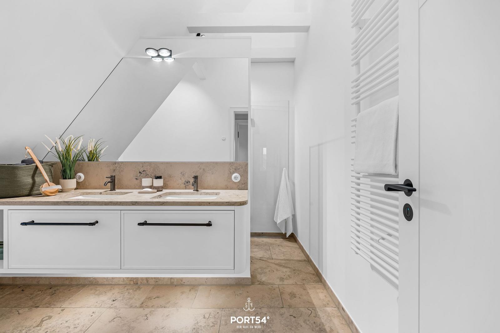 Badezimmer mit Doppelwaschbecken, Spiegelschrank und Heizkörper