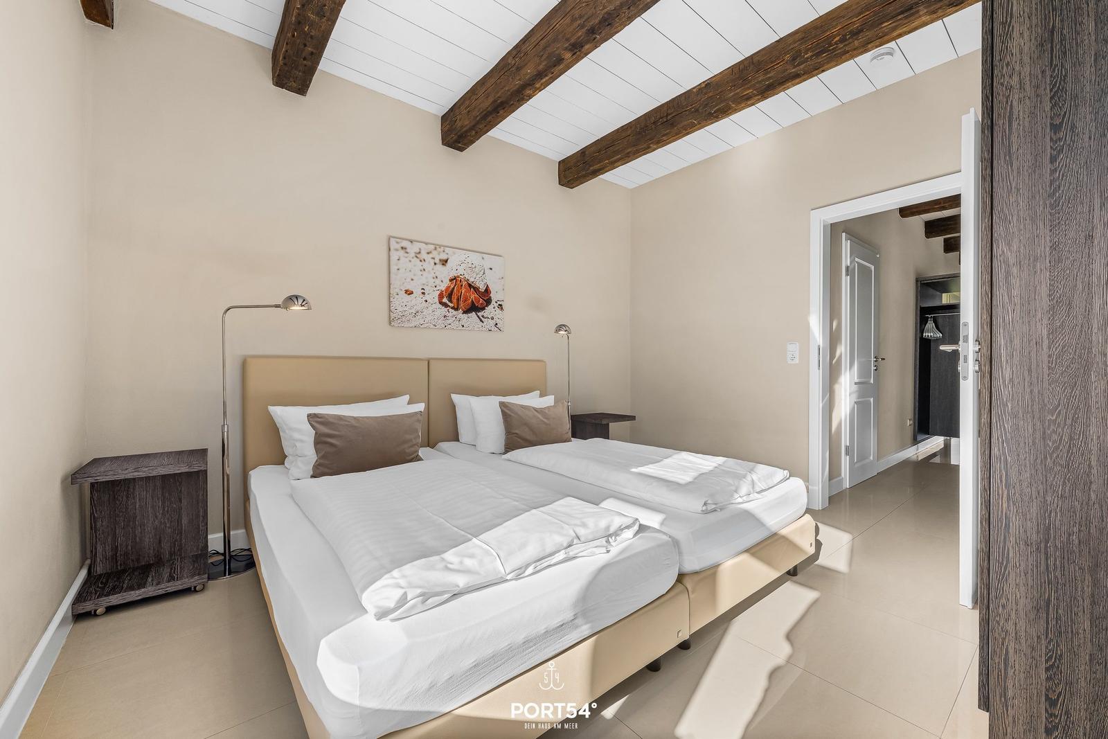 Schlafzimmer mit Doppelbett, Holzbalken und Kunstwerk an der Wand.