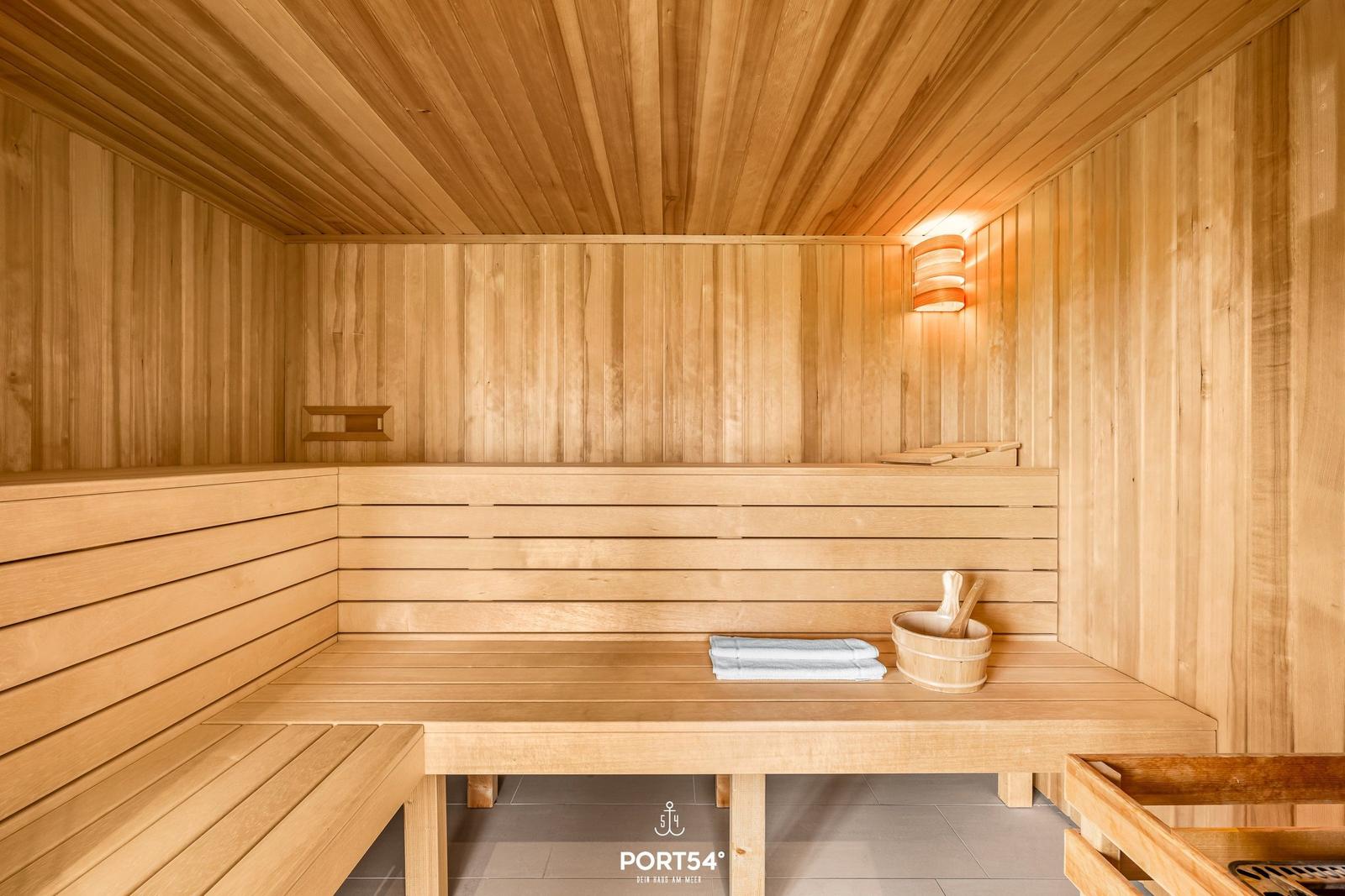 Holzsauna mit Sitzbänken, Handtuch und Eimer.