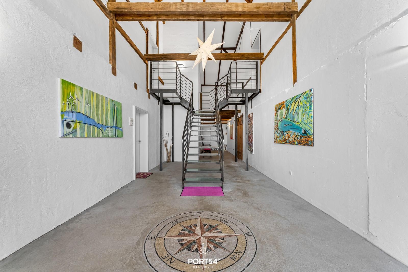 Hallenflur mit Treppe, Wandkunst und Bodenmosaik mit Kompass.