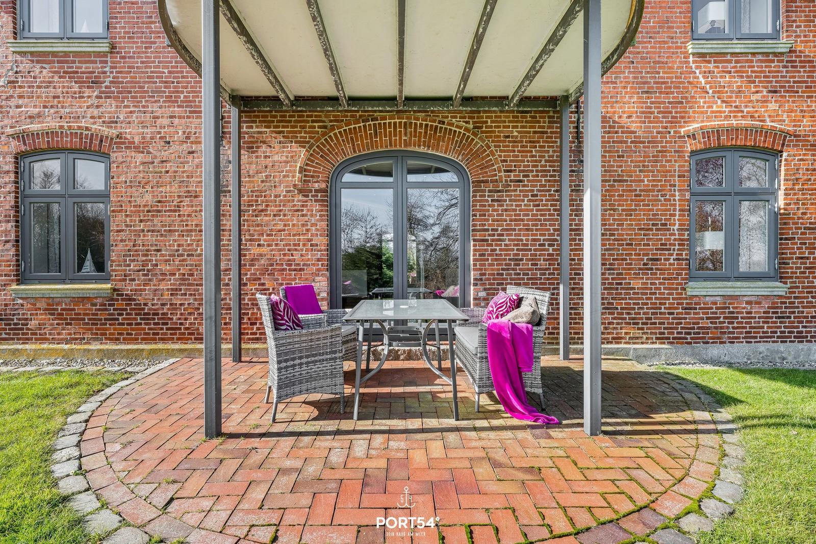 Runder Balkon mit Sitzgruppe und Glas-Tisch vor Backsteinhaus