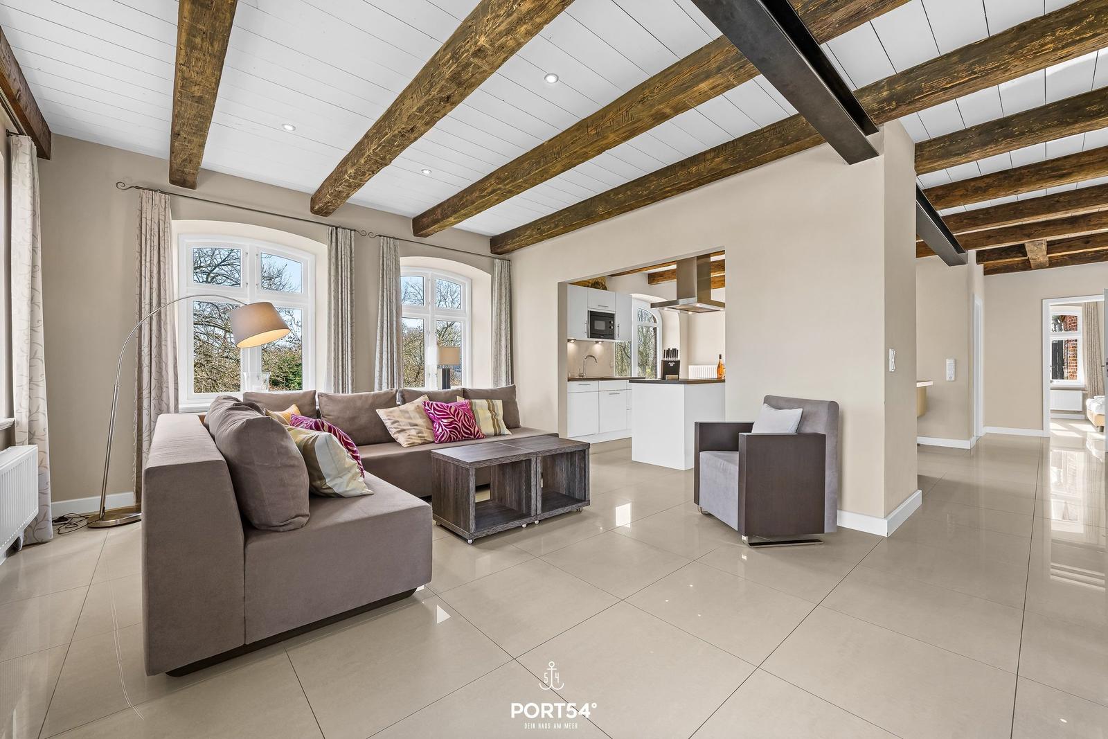 Wohn- und Küchenbereich mit Holzbalkendecke und großem Sofa.