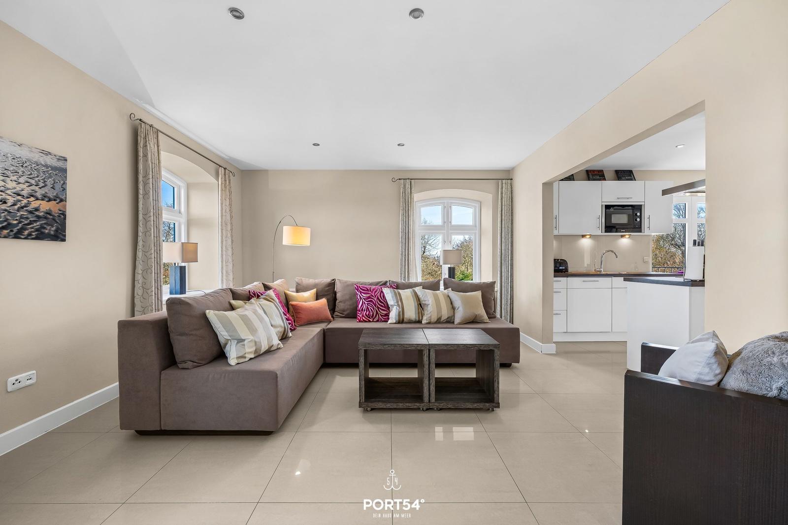 Wohnzimmer mit Ecksofa, Couchtisch und Blick in die Küche.