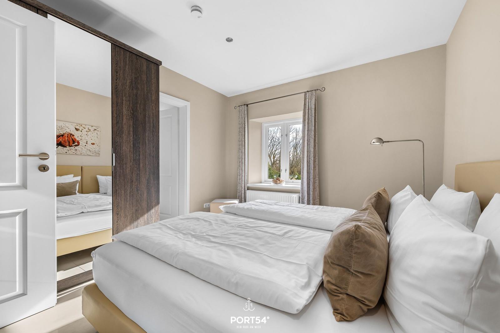 Schlafzimmer mit Doppelbett, Fenster und Spiegeltür