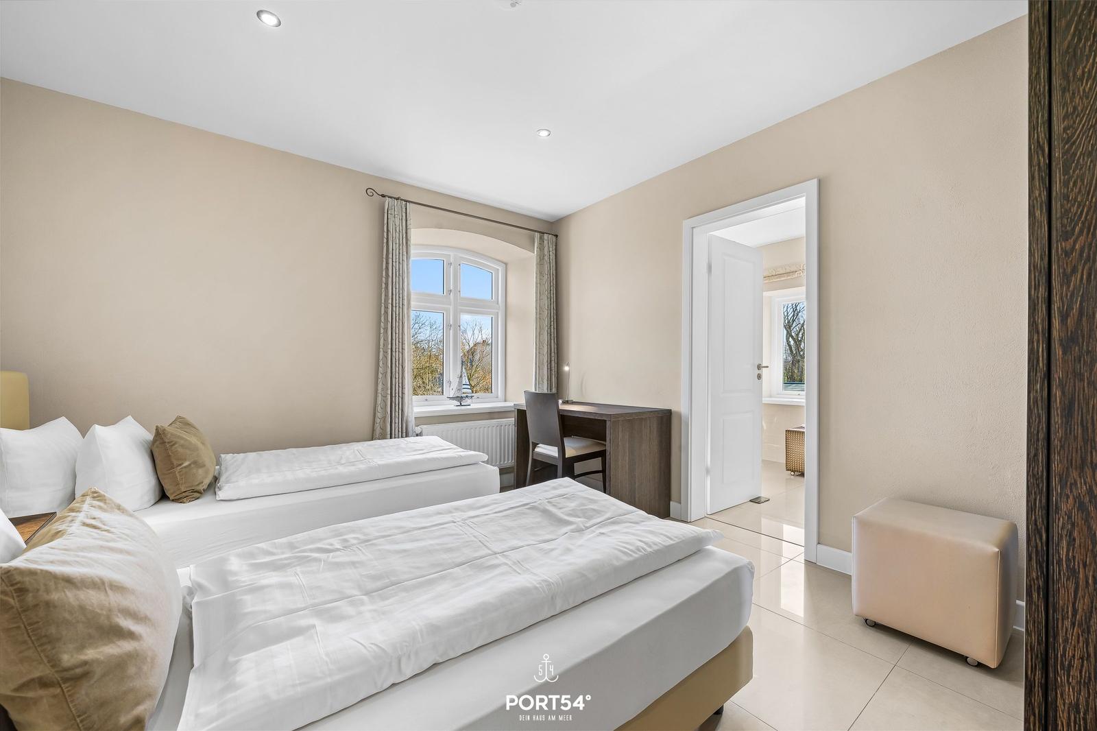 Zimmer mit zwei Betten, Schreibtisch und Blick aus dem Fenster.