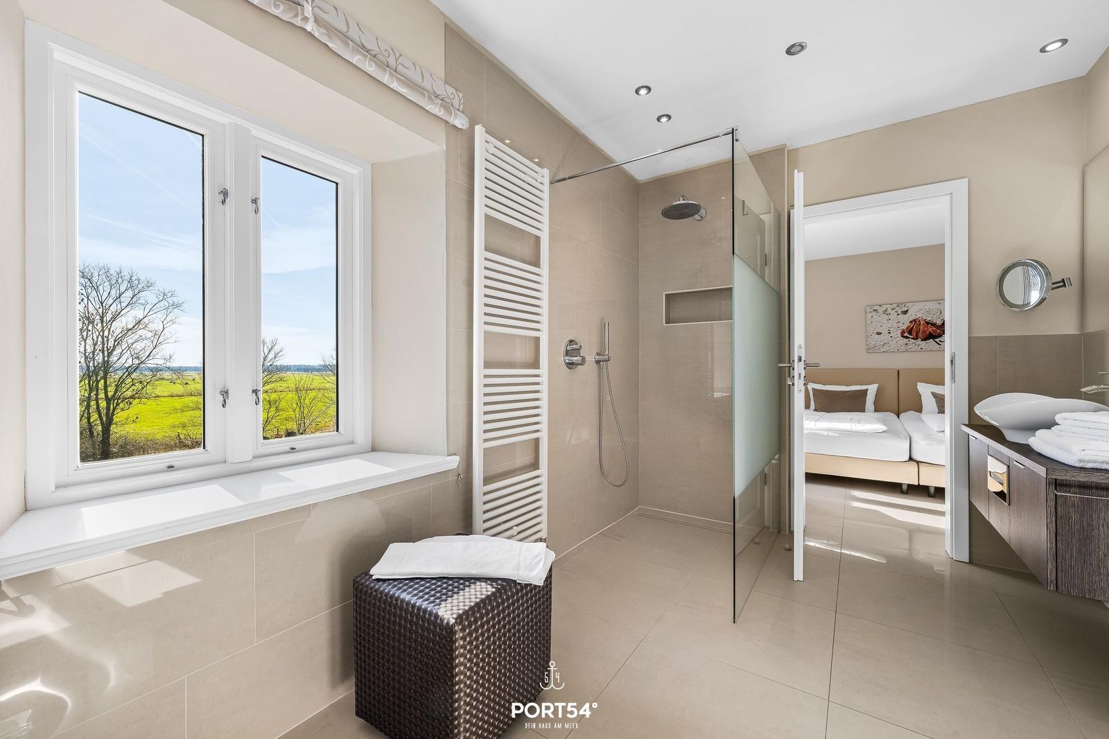Badezimmer mit Dusche, Fensterblick auf Felder und Blick in Schlafzimmer