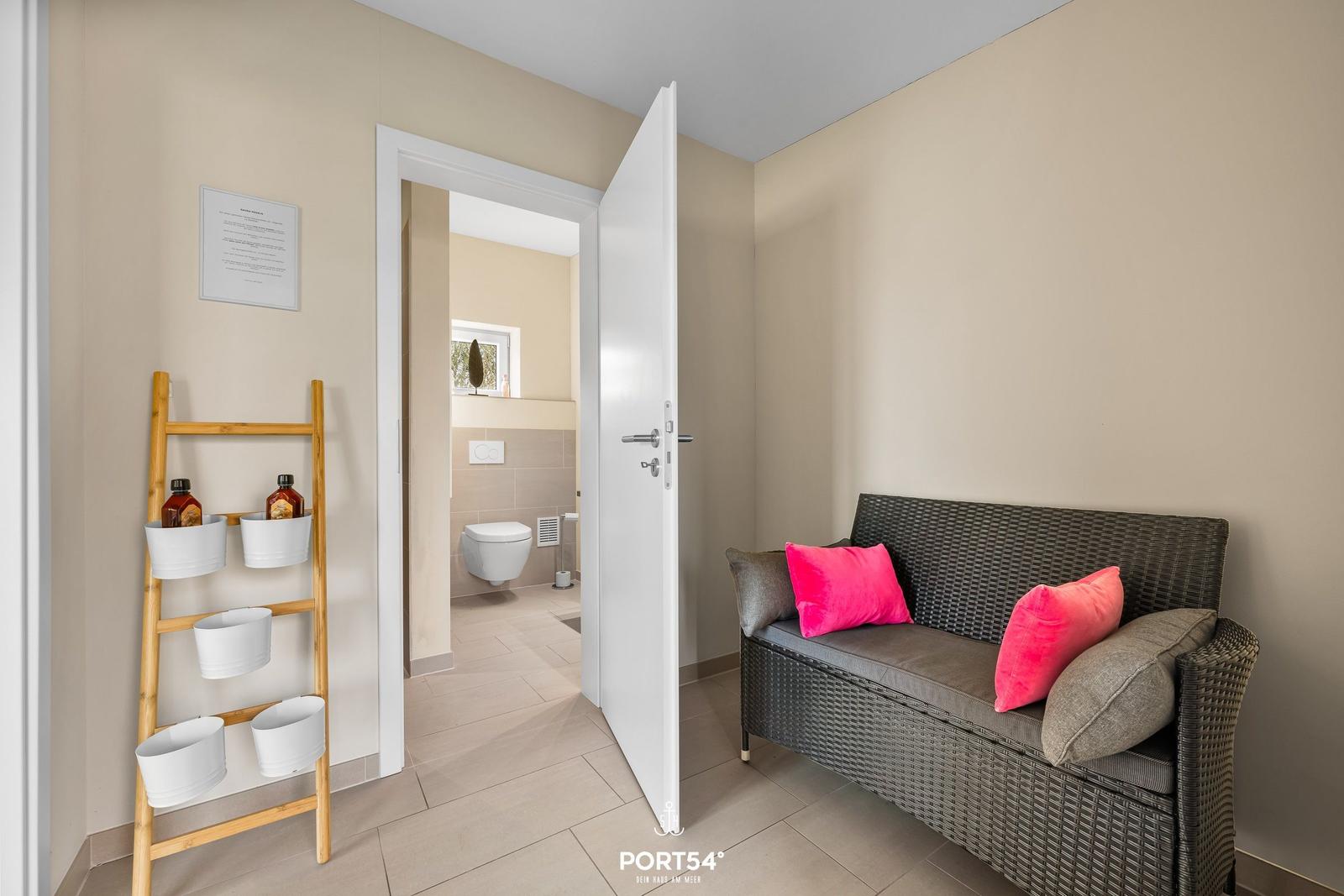 Flur mit Sitzbank und Blick in die Toilette.