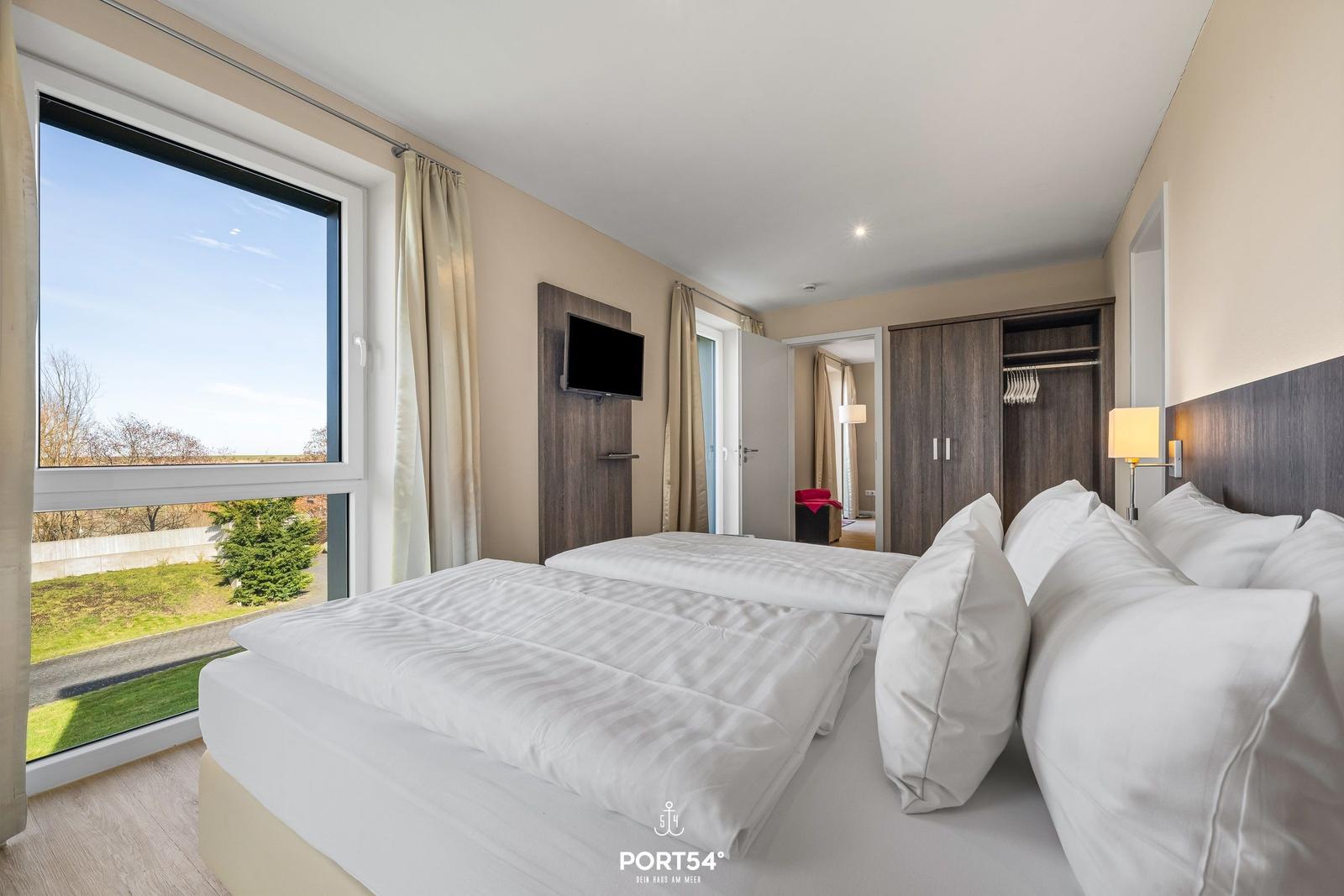 Zimmer mit Doppelbett, Fensterblick und Kleiderschrank.