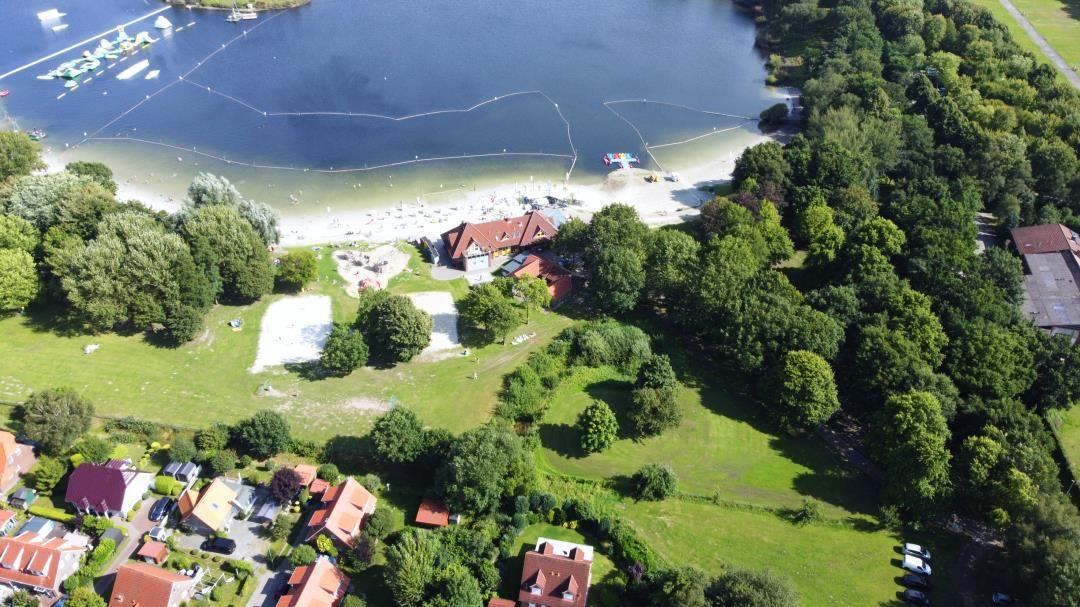 Aussicht auf See mit Strand, Booten und umliegenden Grünflächen.