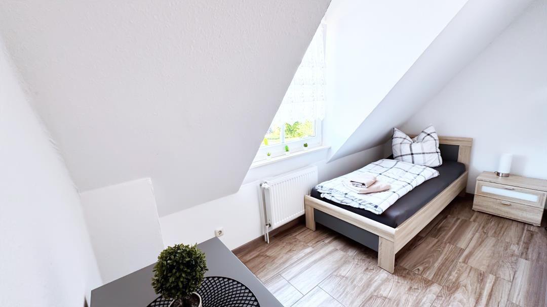 Schlafzimmer mit Dachschrägen, Bett, Nachttisch und Fenster mit Blick.