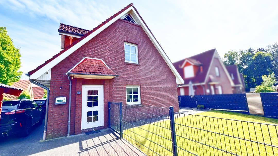 Rotes Backsteingebäude mit weißer Tür und gepflegtem Garten.