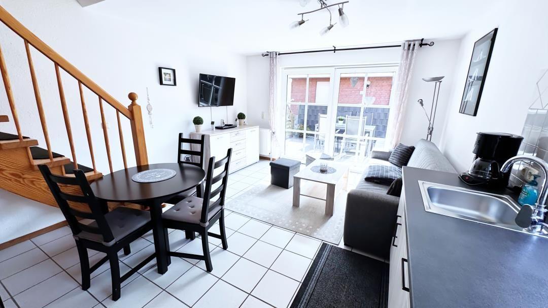 Wohnung mit Essbereich, Küche und Balkon. Treppenhaus links.